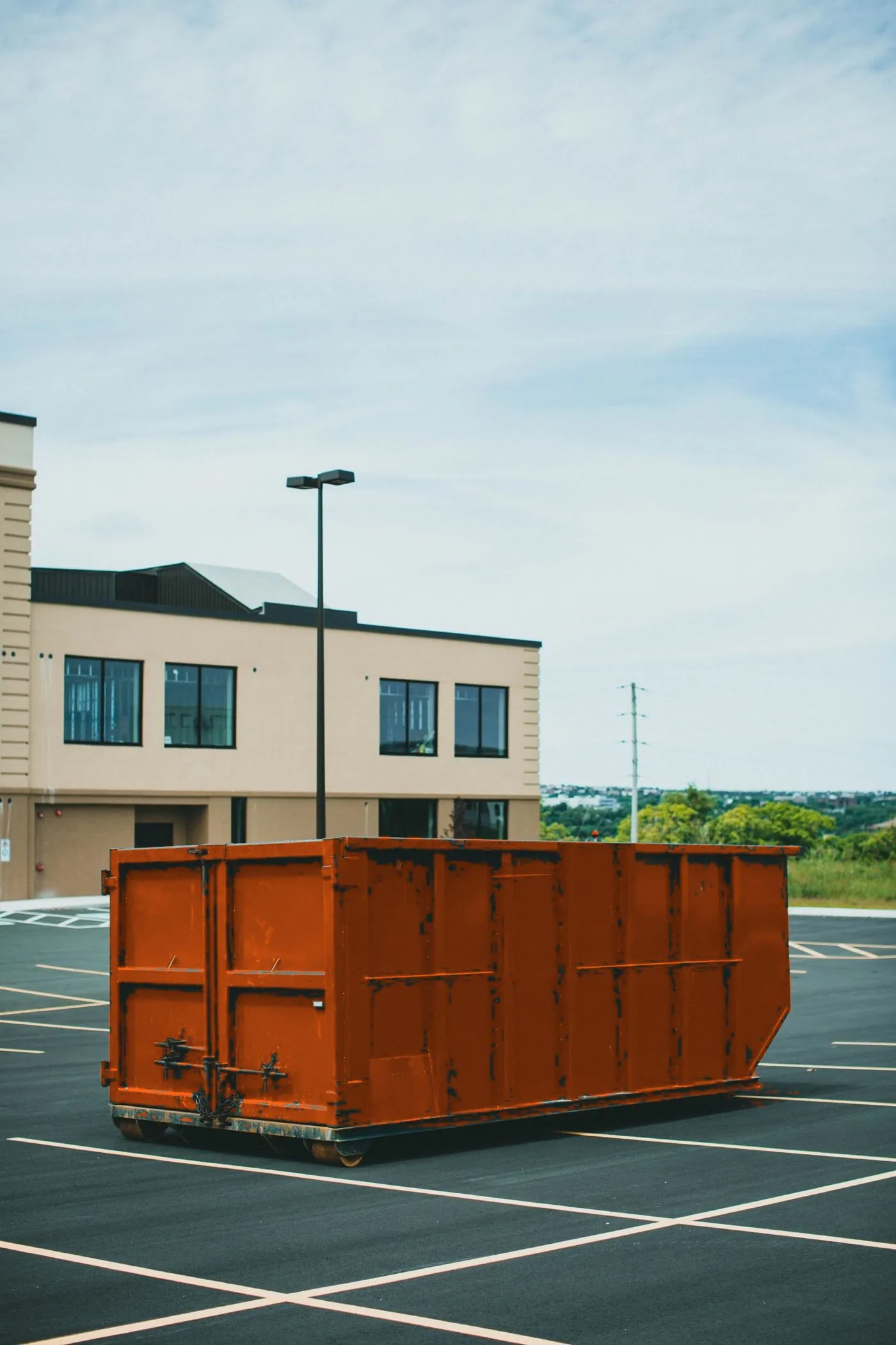Navy blue roll-off dumpster positioned on a paved lot